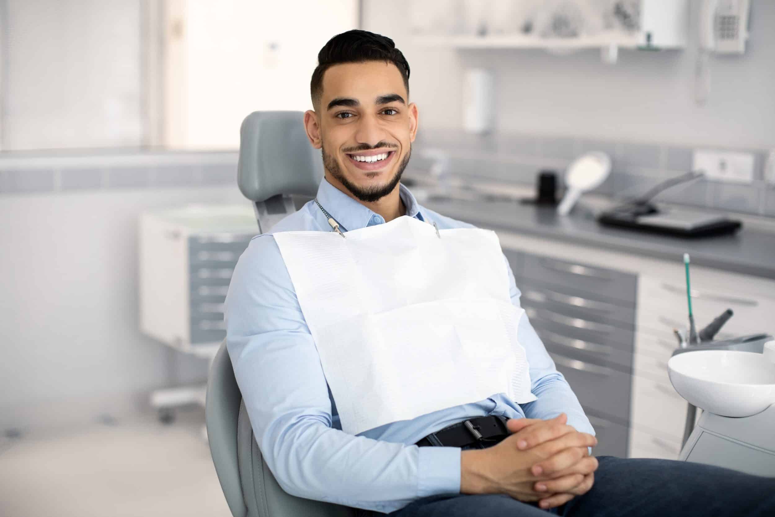 A man sitting in a dentist’s chair and smiling