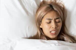 Woman laying in bed and grinding her teeth in need of Botox treatments