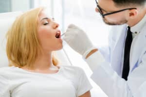 Dentist examining patient’s teeth during dental checkup and oral cancer screening in clinic